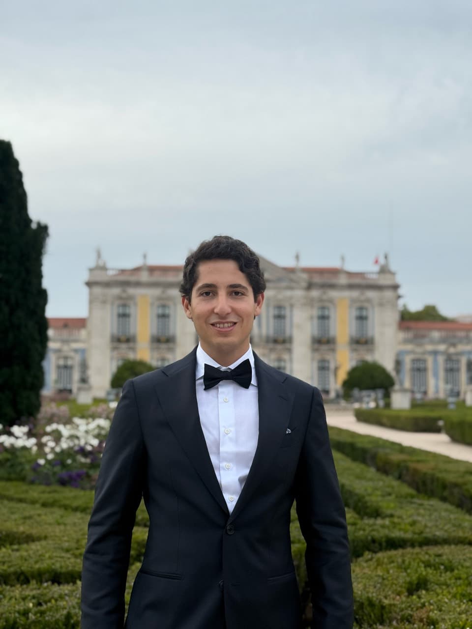 Diego Casabuena, founder of Lokos, wearing a tuxedo in a garden in front of a historic building